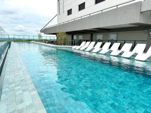 a swimming pool with white chairs in a building at STAY ID Vida Urbana in Goiânia