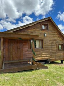 uma cabana de madeira com um alpendre num campo em Guanumby Cabañas em Tandil