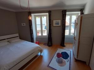 een slaapkamer met een bed, 2 ramen en een tapijt bij Tulle : bel appartement lumineux en centre ville in Tulle