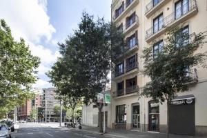 un bâtiment situé dans une rue avec des arbres devant elle dans l'établissement Charming Flats by Aspasios, à Barcelone