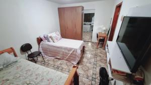 ein Wohnzimmer mit einem Bett und einem TV sowie ein Schlafzimmer in der Unterkunft Kitnet confortável em paulinia in Paulínia