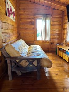 a bed in a log cabin with a window at Guanumby Cabañas in Tandil