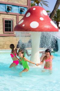 three girls playing in a pool with a red mushroom umbrella at H10 Suites Lanzarote Gardens in Costa Teguise