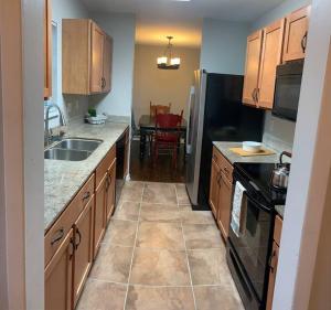 a kitchen with wooden cabinets and a black refrigerator at *3 blocks from AT&T Stadium* 2 bedroom-sleeps 6 in Arlington