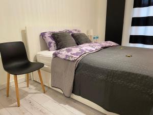 a bedroom with a bed and a black chair at Boznicza Modern Apartment, self check-in 24h, free parking in Poznań