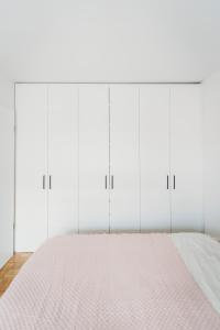 a white bedroom with a bed and white cabinets at Peaceful Little Retreat, spacious free garage park in Ljubljana