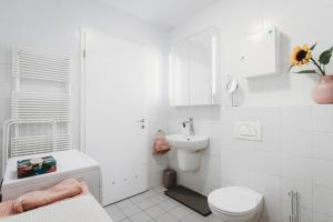 a white bathroom with a toilet and a sink at Peaceful Little Retreat, spacious free garage park in Ljubljana