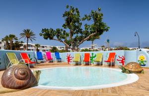 a pool with colorful chairs and a shell in the middle at H10 Suites Lanzarote Gardens in Costa Teguise