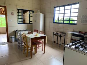 een keuken met een tafel en een witte koelkast bij Casa para Temporada - Luminárias MG in Luminárias