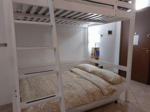 een wit stapelbed in een witte kamer met een bed bij Smile Home! Graziosa casa con parcheggio e giardino in Bovísio-Masciago Milanese