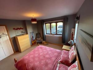 a bedroom with a pink bed and a window at Kisumu in Orkney