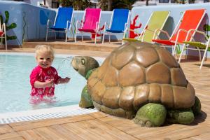 a child in a pool next to a turtle statue at H10 Suites Lanzarote Gardens in Costa Teguise