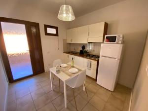 a small kitchen with a table and a white refrigerator at La Collina: Il maestrale in Castiadas