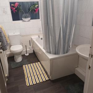 a bathroom with a tub and a toilet and a sink at 2 bed apartment in Whitefield