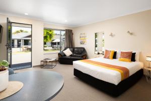 Centre Court Motel في بلينهايم: غرفة نوم مع سرير مزدوج كبير وأريكة