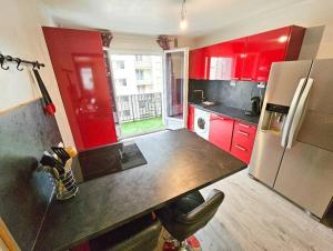 La cuisine est équipée de placards rouges et d'un réfrigérateur. dans l'établissement Le Bergson 3 chambres Stationnement gratuit, à Saint-Étienne