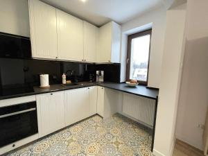 a kitchen with white cabinets and a window at Dom na Słowiańskiej in Szczawno-Zdrój