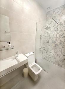 a white bathroom with a toilet and a shower at Appartement Palms Abidjan in Abidjan