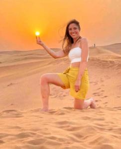 een vrouw op het strand met een licht in haar hand bij Merzouga luxurious Camps in Merzouga
