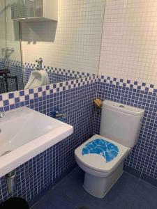 W wyłożonej niebieskimi kafelkami łazience znajduje się toaleta i umywalka. w obiekcie Studio-Loft con Terraza w Madrycie