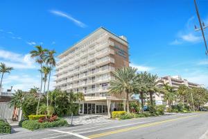 a large building with palm trees in front of a street at Sands Harbor Resort and Marina in Pompano Beach