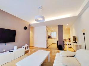 a living room with a white couch and a flat screen tv at Apartamento, piscina y parking Granada Tico Medina in Granada