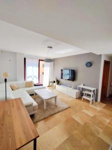 uma sala de estar com um sofá branco e uma mesa em Apartamento, piscina y parking Granada Tico Medina em Granada