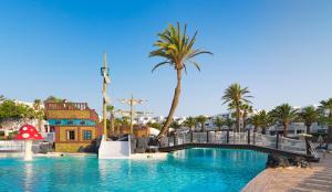 a pool at a resort with palm trees and a bridge at H10 Suites Lanzarote Gardens in Costa Teguise