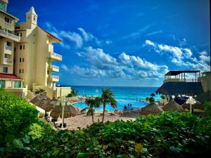 a hotel and a beach with umbrellas and the ocean at Cancun Plaza - Best Beach in Cancún