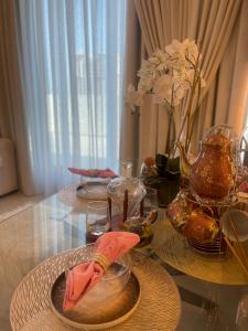 una mesa con platos y un jarrón con flores. en Shared Ensuite BURJ Khalifa VIEW King Bedroom in 2Bed near Dubai Mall 8mins away en Dubái