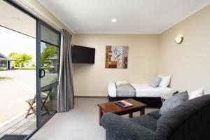a living room with a couch and a bed at Centre Court Motel in Blenheim