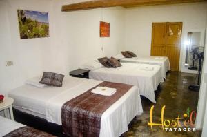a hotel room with three beds with white sheets at Hostel Tatacoa in Villavieja