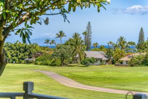 a golf course with palm trees and a house at Grand Champions 163 in Wailea