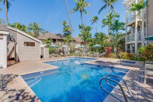 a swimming pool in front of a house with palm trees at Grand Champions 163 in Wailea