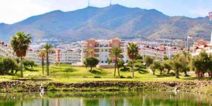 a resort with palm trees and a body of water at Beautiful apartment with pools, playground and paddle tennis - Family friendly and near Vithas Hospital - Free parking in garage in Benalmádena