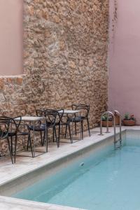 - un groupe de tables et de chaises à côté de la piscine dans l'établissement Art Suites Athens, à Athènes