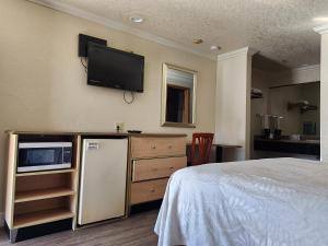 a bedroom with a refrigerator and a tv on the wall at Budget Inn in Corcoran