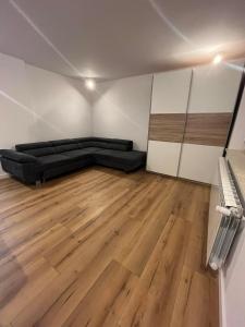 Habitación con sofá negro y suelo de madera. en Piasecki Apartamenty en Lublin