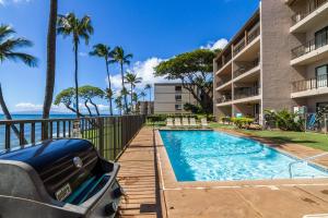 a swimming pool in front of a building with the ocean at Lauloa 105 in Wailuku