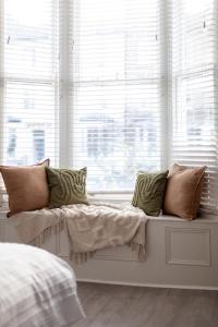 un asiento junto a la ventana con almohadas en el dormitorio en Arte Stays - 2 Bed Luxurious Flat, Garden, 5min Dalston st., Parking Available, Serviced Accommodation - up to 5 ppl en Londres
