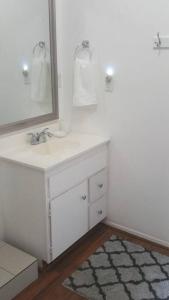 a white bathroom with a sink and a mirror at River Retreat Cabin in Three Rivers - near SNP in Three Rivers