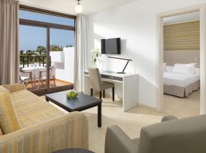 a hotel room with a bed and a desk at H10 Suites Lanzarote Gardens in Costa Teguise