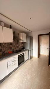 eine leere Küche mit weißen Schränken und Geräten in der Unterkunft Appartement à 14 min de la place Jamaà el Fna in Marrakesch