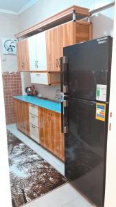 a kitchen with a black refrigerator and wooden cabinets at ١٠ب شارع حافظ رمضان مكرم عبيد أمام سيتي سنتر مكرم عبيد in Cairo