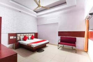 een slaapkamer met een bed en een rode stoel bij OYO Flagship Hotel Preet Palace in Rānchī