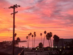 a sunset with palm trees in front of the ocean at Howard Johnson by Wyndham Santa Cruz Beach Boardwalk in Santa Cruz