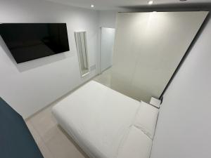 um quarto branco com um sofá branco e uma televisão em Fuente Dulce em Orzola