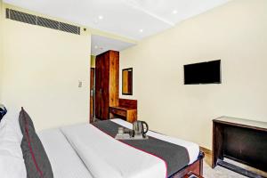 a bedroom with a bed and a flat screen tv at Townhouse Prakash continental Near Netaji Subhash Place Metro Station in New Delhi