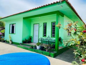 a green house with a blue at Casa acolhedora ideal para famílias, com Wi-Fi rápido, cozinha exclusiva e equipada, varanda com churrasqueira - A apenas 1 km da praia do bairro e 5 km da charmosa Praia da Vila in Imbituba