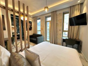 Dormitorio con cama, escritorio y TV en Royal Gold City Suites by Estia, en Heraclión